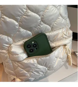 Detail view of the large front zipper pocket on a white quilted backpack with woven rope puller