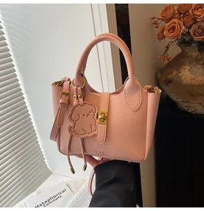 Detailed close-up of pink litchi grain bucket bag with golden lock and dog charm