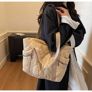 Quilted beige puffer tote bag detail on shoulder showing spacious capacity and dual front zippers