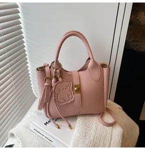 Detail of pink lychee leather bucket bag featuring a golden metal twist lock and handle