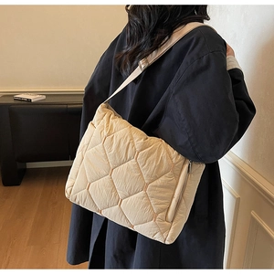 Detail of cream quilted tote bag featuring geometric patterns and adjustable shoulder strap