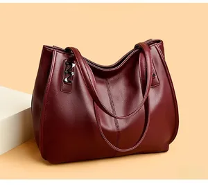 Macro view of burgundy pebble leather tote bag featuring a polished silver metal M hardware