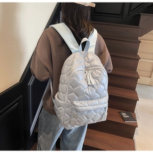 Close-up of quilted heart-pattern backpack with blue straps on a model in home setting