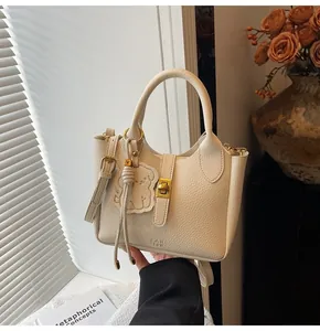Detail of cream lychee texture bucket bag with metal twist lock and bear charm