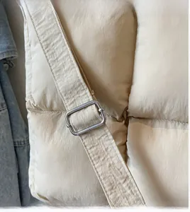 Close-up of beige quilted tote bag showing adjustable shoulder strap and silver metal buckle