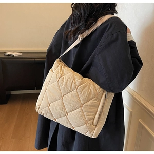 Detail of beige quilted puffer bag featuring hexagonal stitching and adjustable strap