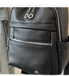 Detail of black pebbled leather texture and silver zipper with ring pull on backpack