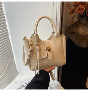 Detail of off-white lychee pattern bucket bag with bear charm and gold metal hardware