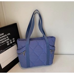Close-up of quilted blue-purple tote bag showing texture and side zipper pockets