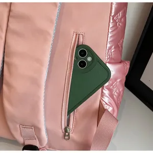 Detail of pink backpack showing zipper pocket with phone inside and butterfly quilting