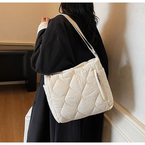 Detail of white quilted tote bag with padded down-like texture and side zipper pocket