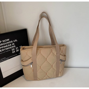 Macro detail of beige quilted tote bag showing rhombus stitching and side zipper