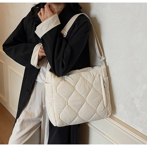 Detailed view of cream quilted nylon crossbody bag with adjustable strap worn by a model