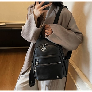 Detail of black pebbled leather backpack showing silver circular metal zippers and pockets