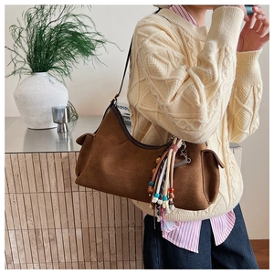 Detail der braunen Wildledertasche mit bunten Perlenquasten und Lederbesatz am Rand