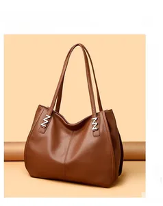 Detail of classic brown leather tote bag showing fine texture and N-shaped metal buckle
