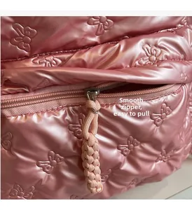 Close-up of pink quilted backpack showing smooth zipper and butterfly embossed texture