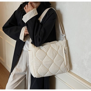 Detail of off-white puffer tote bag featuring diamond quilting and adjustable strap
