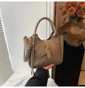 Detail of grey lychee leather bucket bag with dog pendant and gold twist lock closure