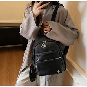 Detail of black lychee grain leather backpack with silver zippers and fabric straps