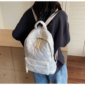 Detail of white quilted backpack with heart pattern stitching and woven straps