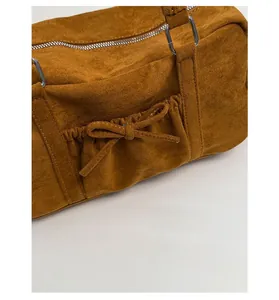 Détail du sac bowling en daim marron avec nœud décoratif et fermeture argentée