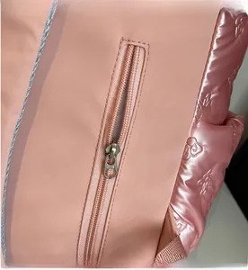 Close-up of smooth metal zipper and quilted floral pattern on pink nylon backpack