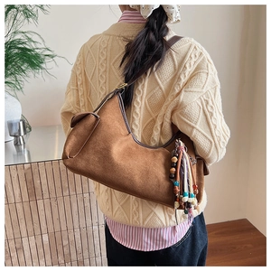 Detail einer braunen Wildleder-Hobo-Tasche mit ethnischem Quasten-Anhänger