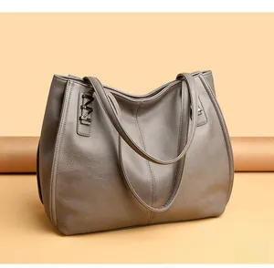 Detail shot of grey faux leather tote bag showing grainy texture and metallic M charm
