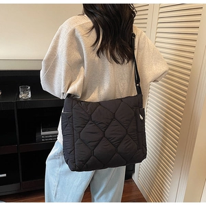 Detail of black quilted shoulder bag featuring adjustable strap and side pocket design