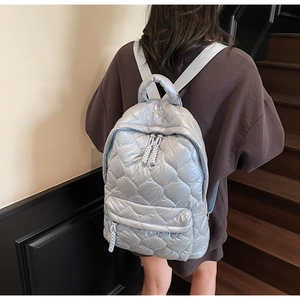 Quilted backpack in light blue featuring diamond patterns and a woven zipper puller