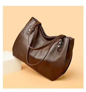 Detailed close-up of dark brown leather texture and silver square metal buckle on handbag
