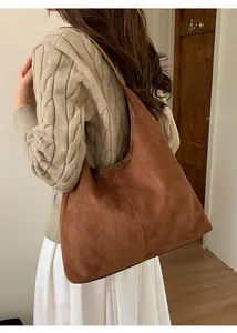 Detail of a large brown suede tote bag featuring central vertical stitching and leather trim