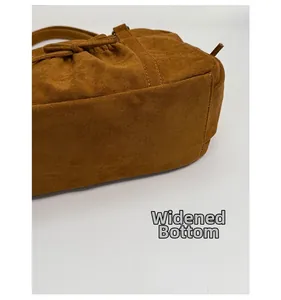 Vue détaillée du fond large et du cordon latéral d'un sac à main en daim marron