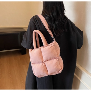 Side view of pink quilted tote bag with soft padded handles worn as a shoulder bag