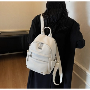 White pebbled leather backpack shown on a model with detailed metal chain zipper