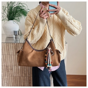 Detail einer dunkelbraunen Wildledertasche mit dekorativem Vintage-Fransenanhänger