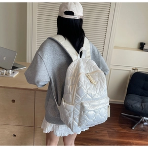 Close-up of white quilted puffer backpack with soft padded nylon texture and zipper detail