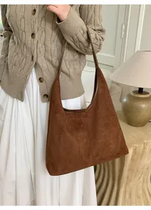 Detailed view of caramel suede shoulder bag with vertical stitching and minimalist hobo shape