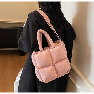 Pink quilted tote bag with puffy texture shown on model from a stylish side-back view