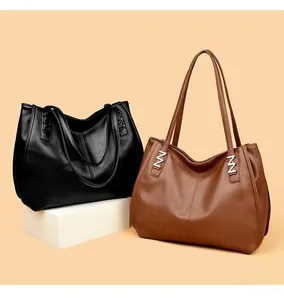 Close-up of black and brown leather tote bags with elegant metallic N-shaped details