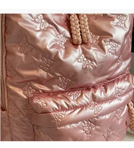 Detail of pink metallic quilted nylon fabric with 3D bow patterns on a backpack