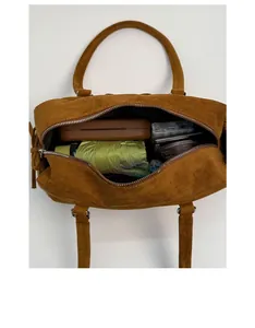 Vue de dessus montrant la grande capacité intérieure de ce sac bowling en daim marron avec objets