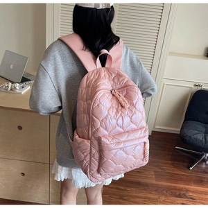 Detailed view of pink quilted backpack featuring heart pattern and large main compartment