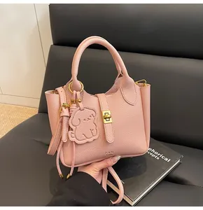 Detailed view of pink lychee leather bucket bag with cute dog charm and golden hardware