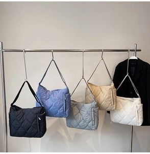 Multiple colors of quilted shoulder bags including black and beige shown hanging