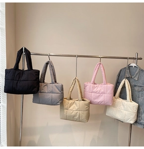 Dettaglio di borse tote trapuntate in nero, beige, rosa e kaki appese in fila