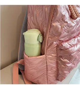 Detailed view of pink quilted backpack side pocket holding a green water bottle