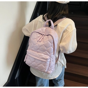 Lavender quilted puffer backpack shown from behind on a model climbing stairs
