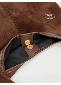 Detail of magnetic snap closure on brown faux suede tote bag with black lining